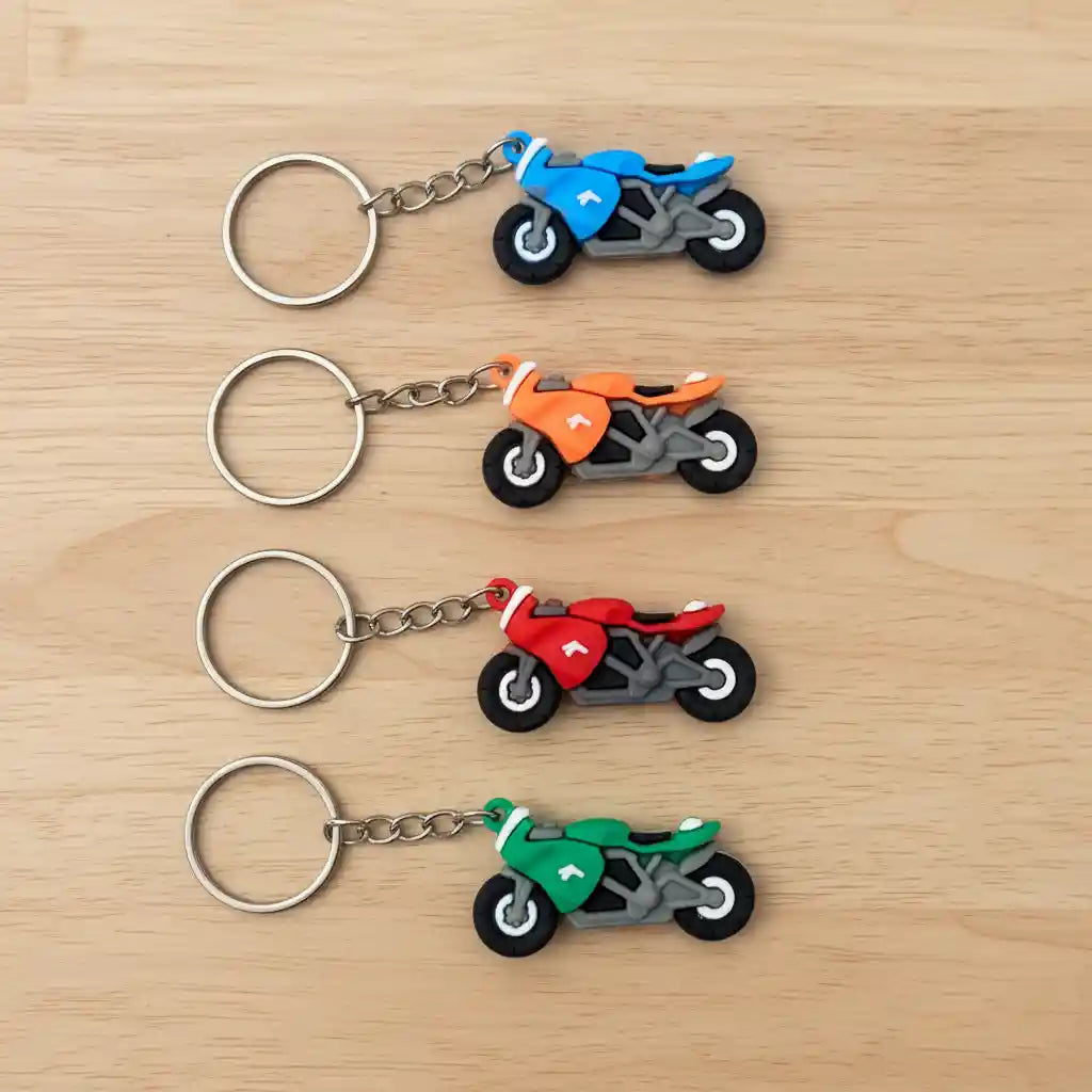 small rubber motorcycle keychains on a light wood table
