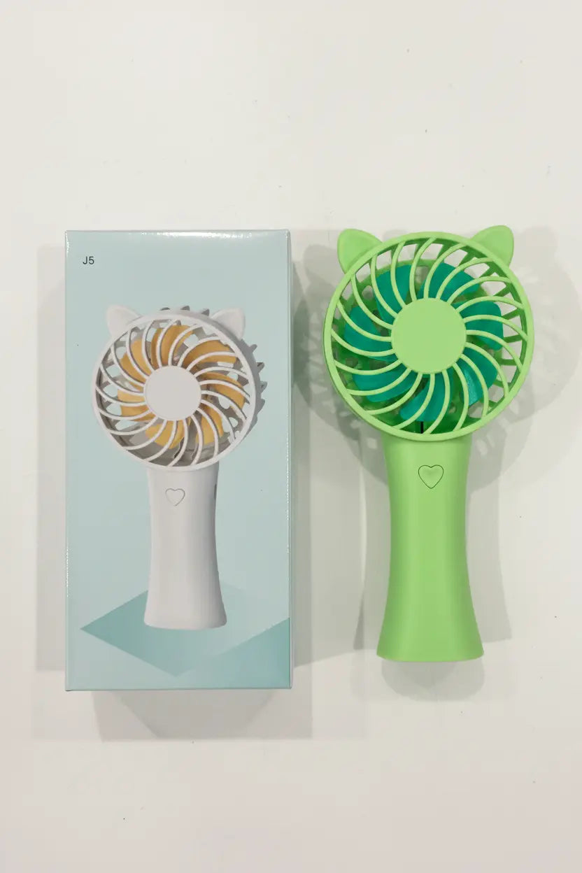 Green handheld fan with cat ear design next to its packaging on a white background