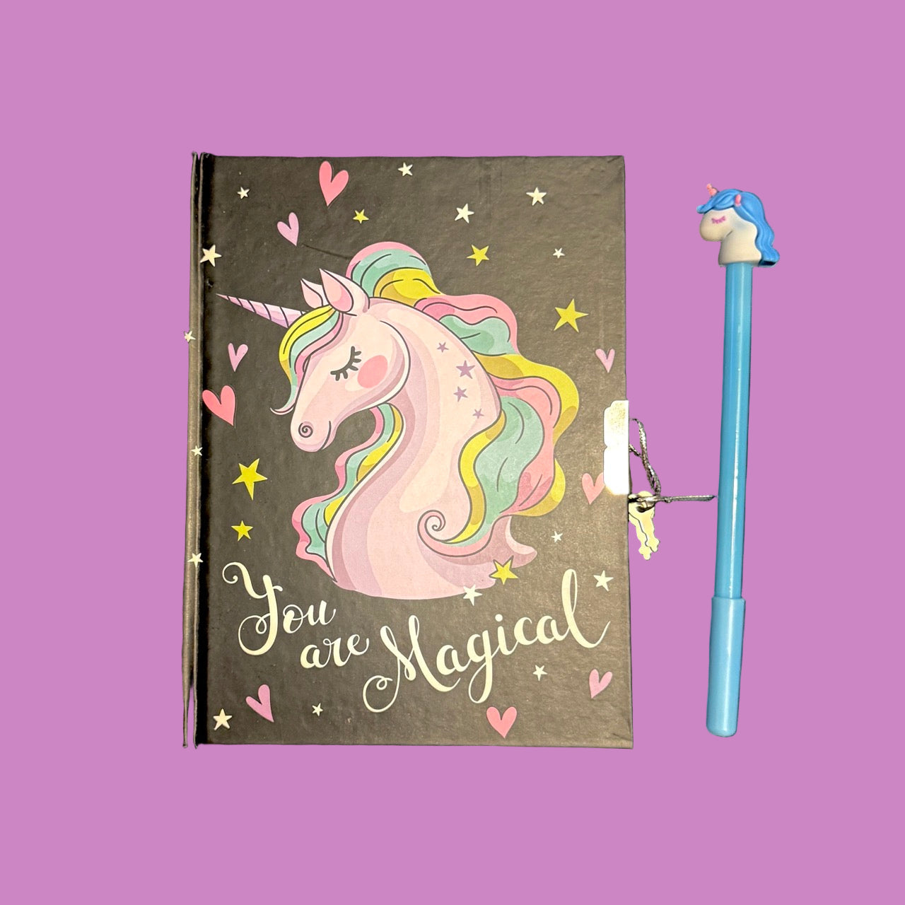 Notebook with unicorn illustration and 'You are Magical' text, accompanied by a blue pen with a unicorn design on a purple
background.