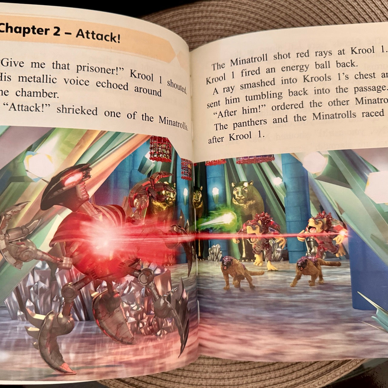 Open book with a fantasy scene featuring robots and creatures, Chapter 2 labeled 'Attack!'.