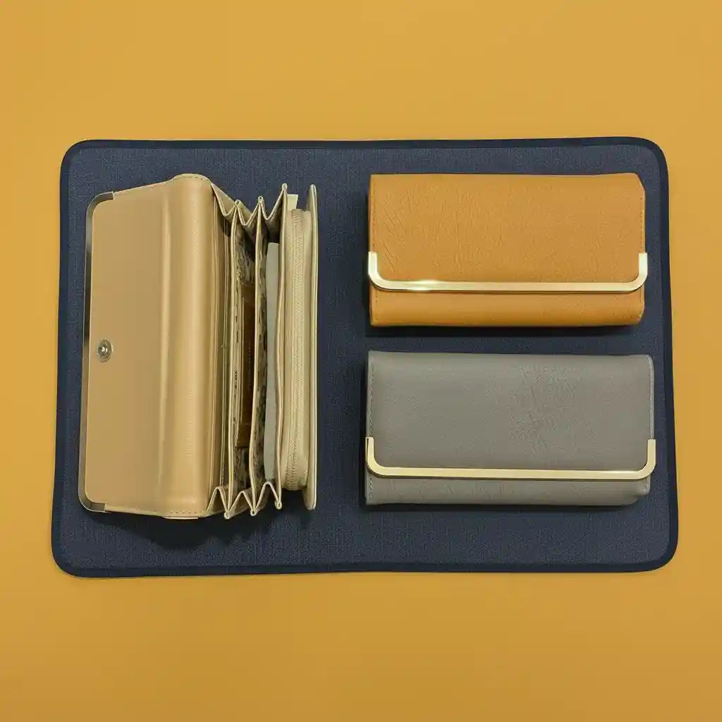 Three clutches in gold, brown, and gray on a dark blue mat with a yellow background