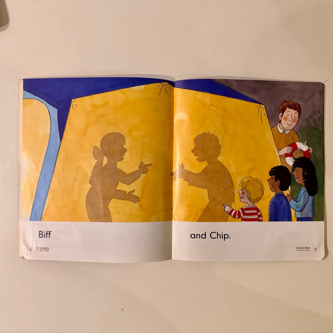 Open book showing illustrations of children and shadows on a yellow background