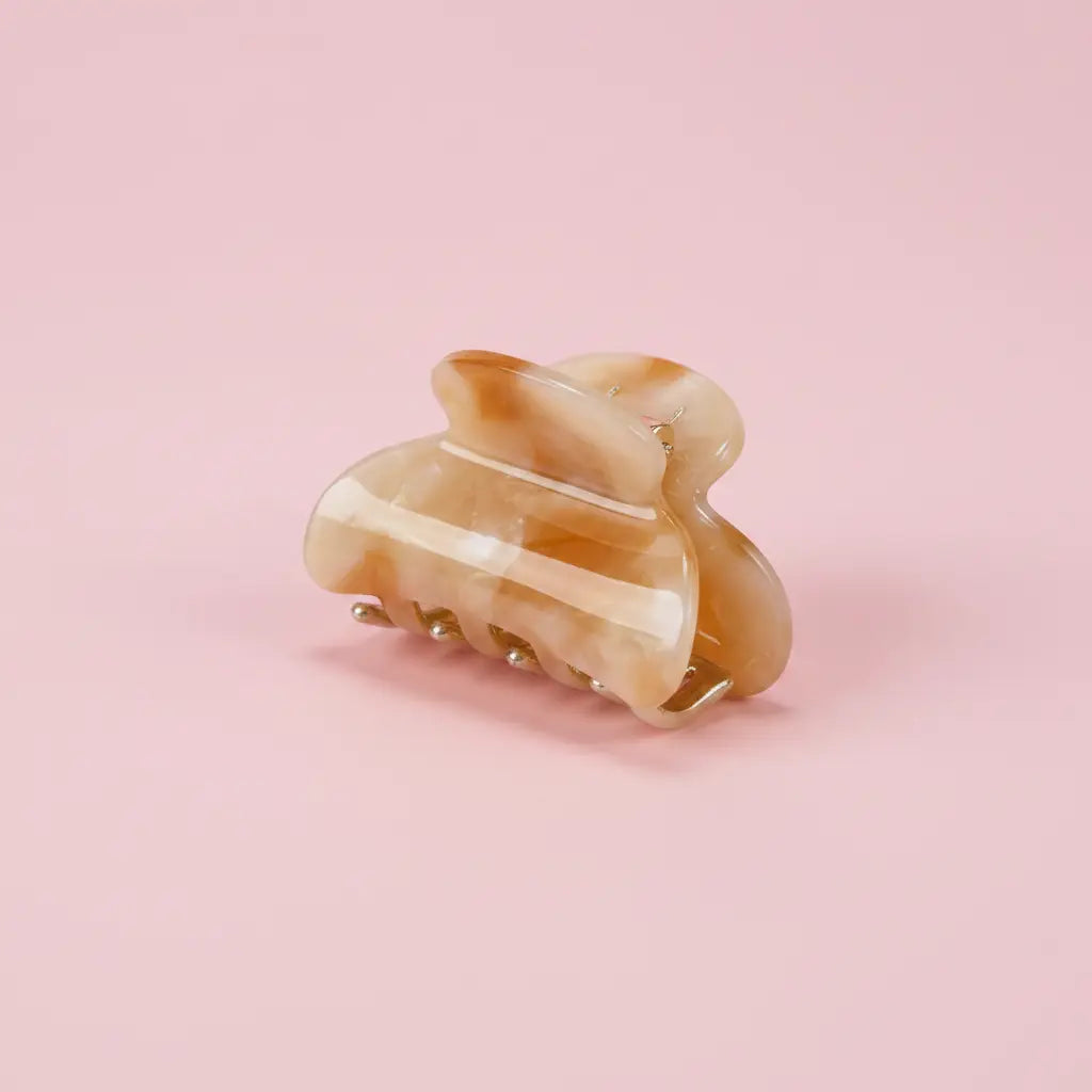 sea shell colored hair clip on a pink background