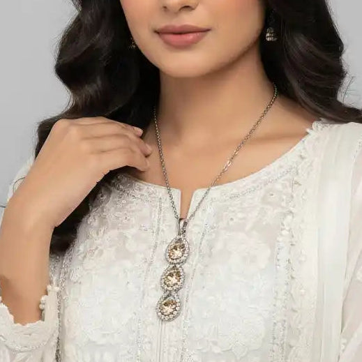 Woman wearing a white embroidered outfit against a gray background