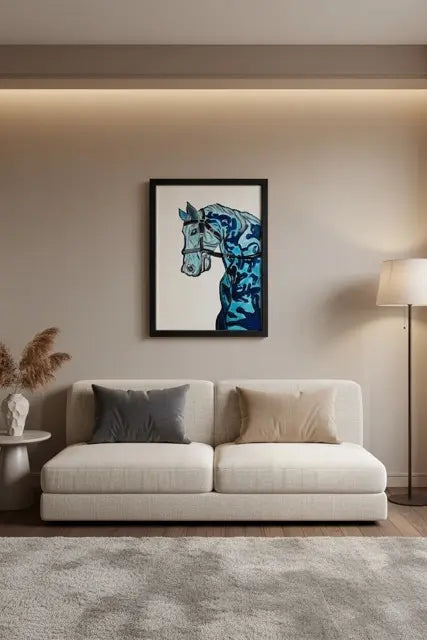 A framed art print of a stylized blue horse head hanging on a beige wall above a modern white sofa in a styled living room setting.