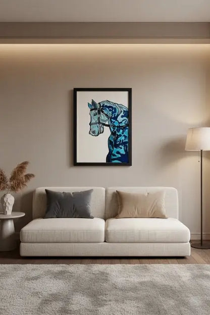 A framed art print of a stylized blue horse head hanging on a beige wall above a modern white sofa in a styled living room setting.