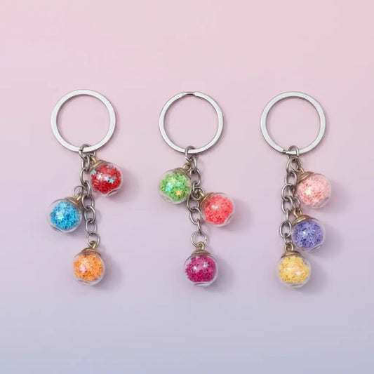 3 little jars with sequins on a light pink background