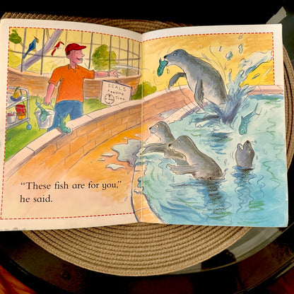 Illustrated book page with a man and seals in an aquarium setting