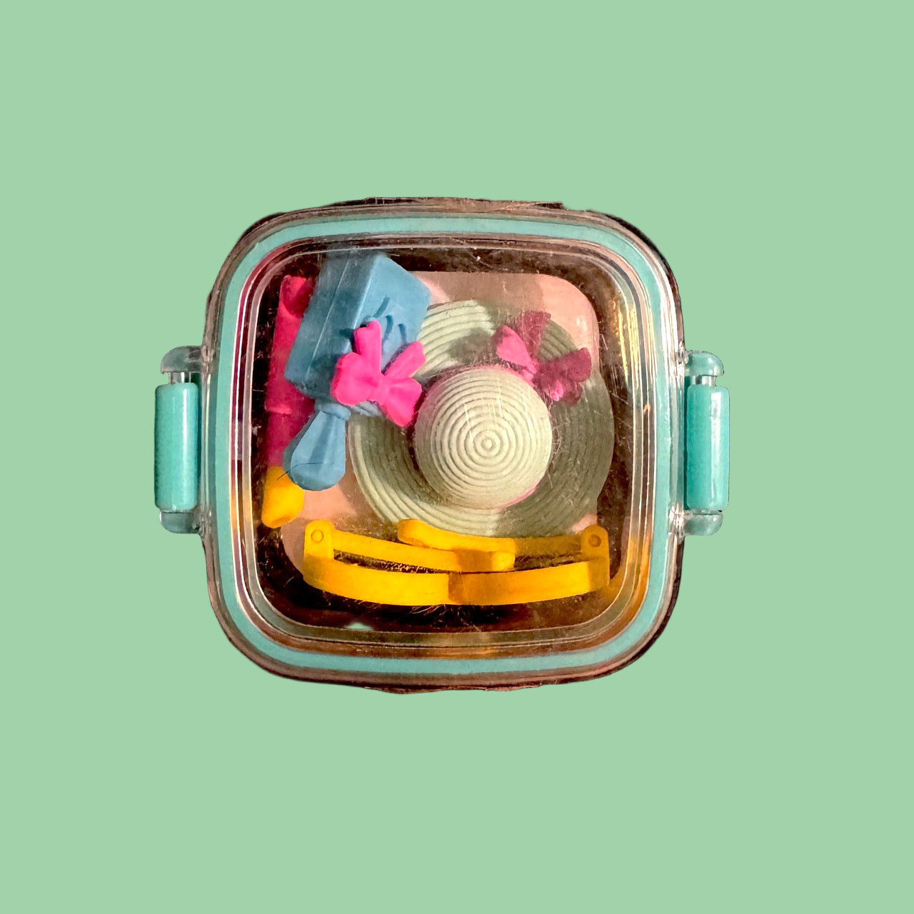 Clear container with colorful erasers o light green background