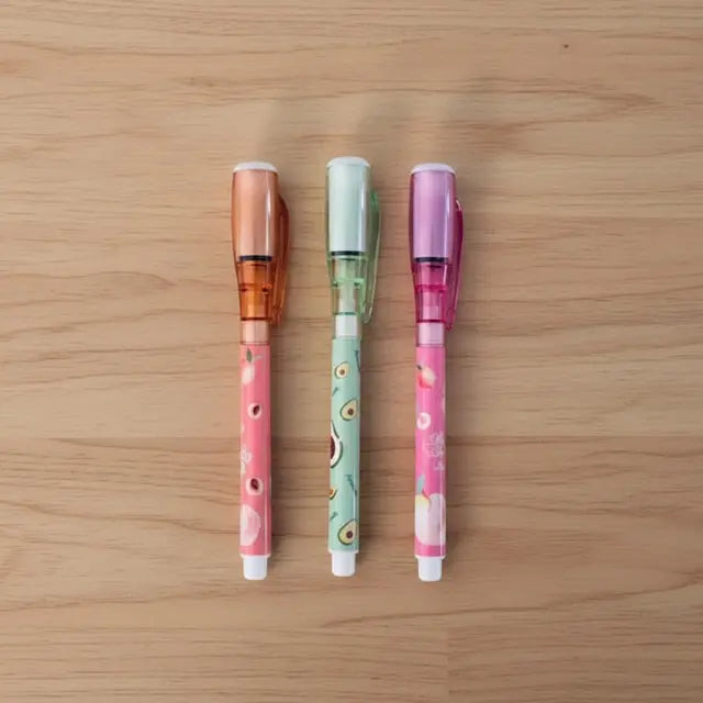 Three colorful pens on a wooden surface