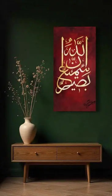 A vertical canvas print featuring elegant gold Arabic calligraphy on a deep red background, displayed on a dark green wall above a mid-century modern wooden console table with a beige ceramic vase.