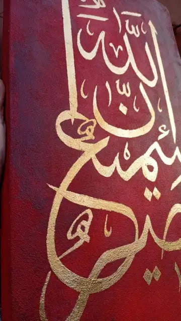A close-up of a red book or cover featuring ornate gold Arabic calligraphy.