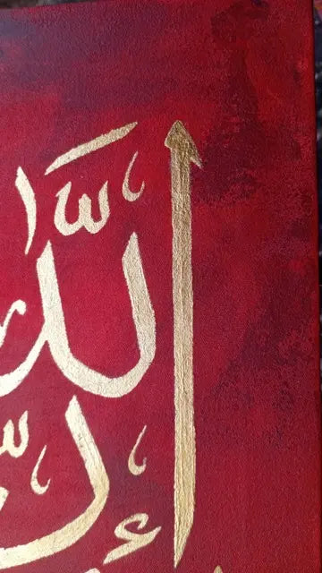 A close-up of a red textured surface featuring metallic gold Arabic calligraphy.