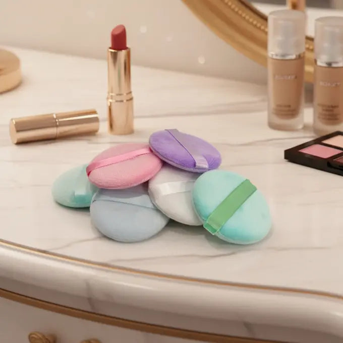 Colorful makeup puffs on a vanity with lipsticks and other products.