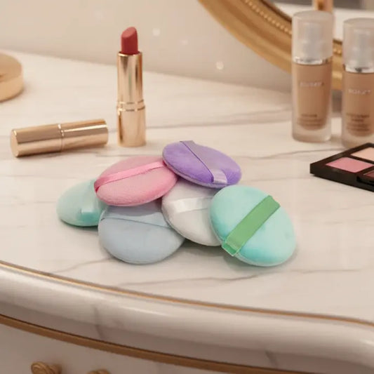 Colorful makeup puffs on a vanity with lipsticks and other products.