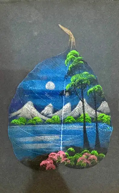 A decorative leaf-shaped object featuring a colorful embroidered landscape design with blue water, white mountains, green trees, pink flowers, and a moon under a dark blue sky, set against a dark gray background.