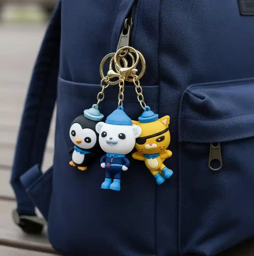 Three cartoon character keychains on a blue backpack