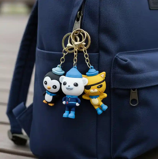 Three cartoon character keychains on a blue backpack