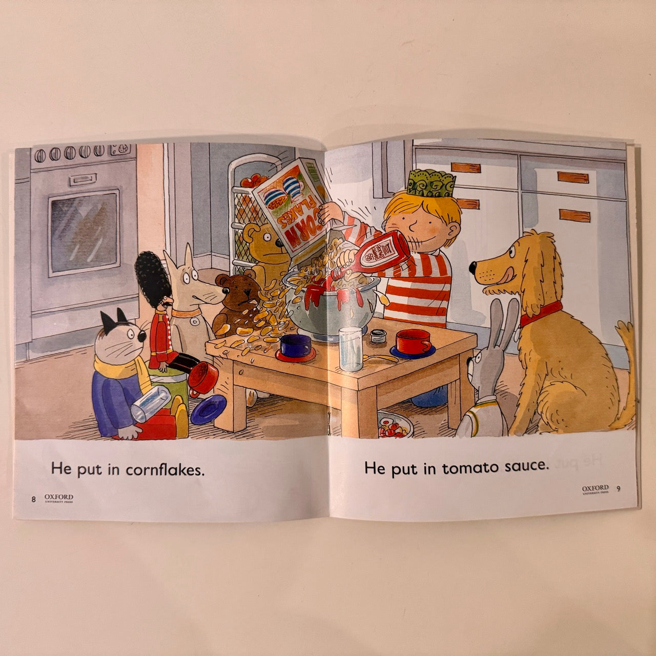 Open book showing a cartoon scene with characters around a table.