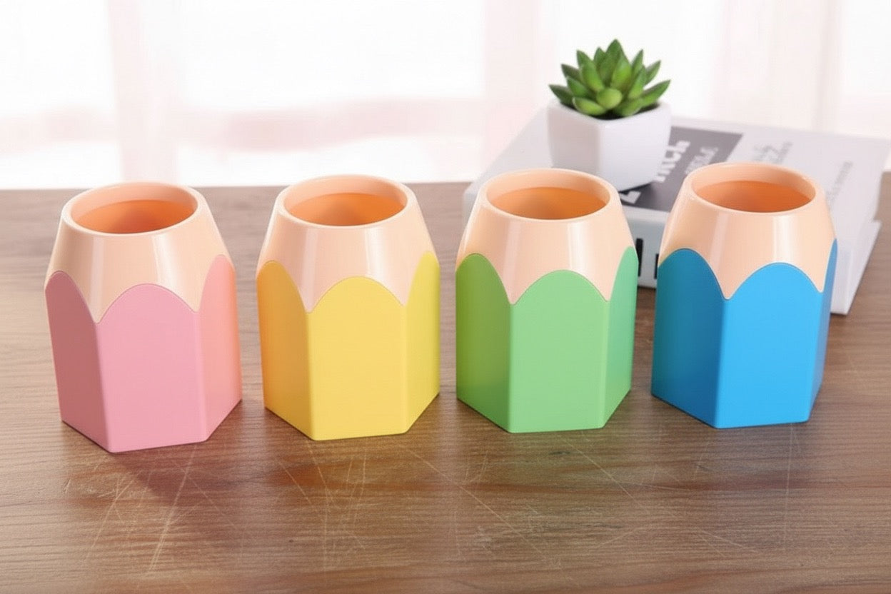 Four colorful pencil-shaped cups on a wooden surface with a blurred indoor background.