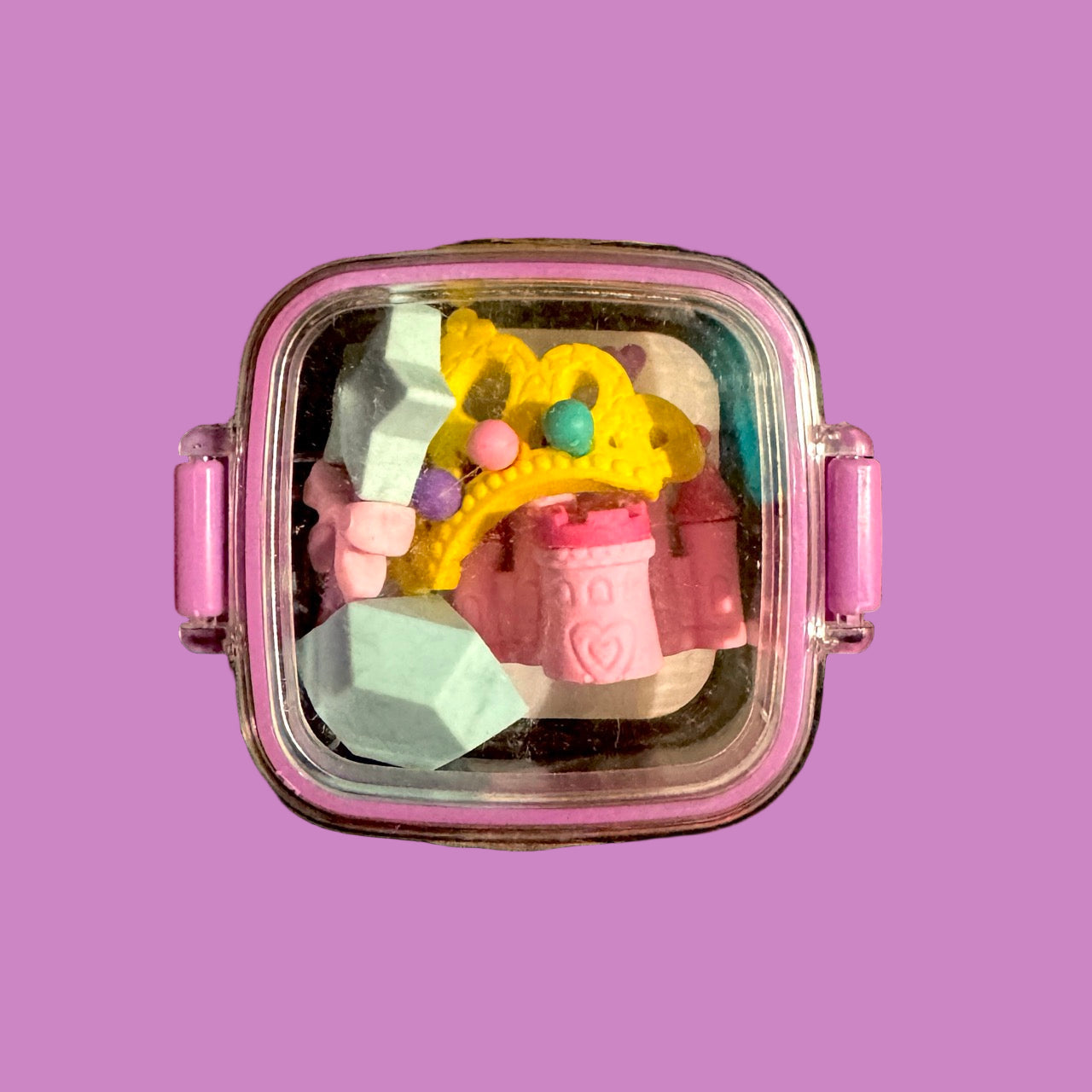 Colorful toy castle in a small transparent container with pink lid on a black background