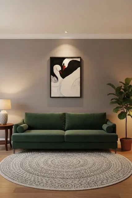 A modern living room setup featuring a dark green velvet sofa, a round patterned area rug, a potted fiddle-leaf fig plant, and a framed swan painting on a warm gray wall.