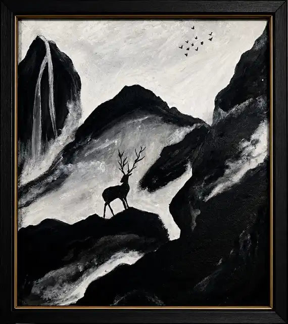 A framed black and white landscape painting featuring a deer silhouette on a rocky peak, a waterfall on the left, and birds in the sky, enclosed in a black frame with a gold inner border.