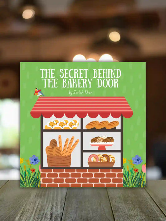 A children's book titled 'The Secret Behind the Bakery Door' by Zarlish Khan, featuring a colorful illustration of a bakery storefront with breads and pastries, displayed on a wooden surface with a blurred cafe background.
