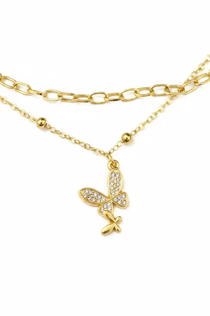 Gold butterfly necklace with clear stones on a white background