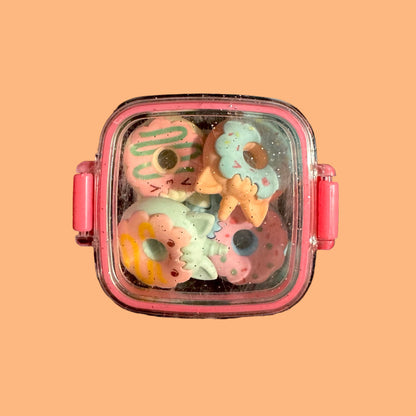 Pink container with colorful donut-shaped objects on a peach background
