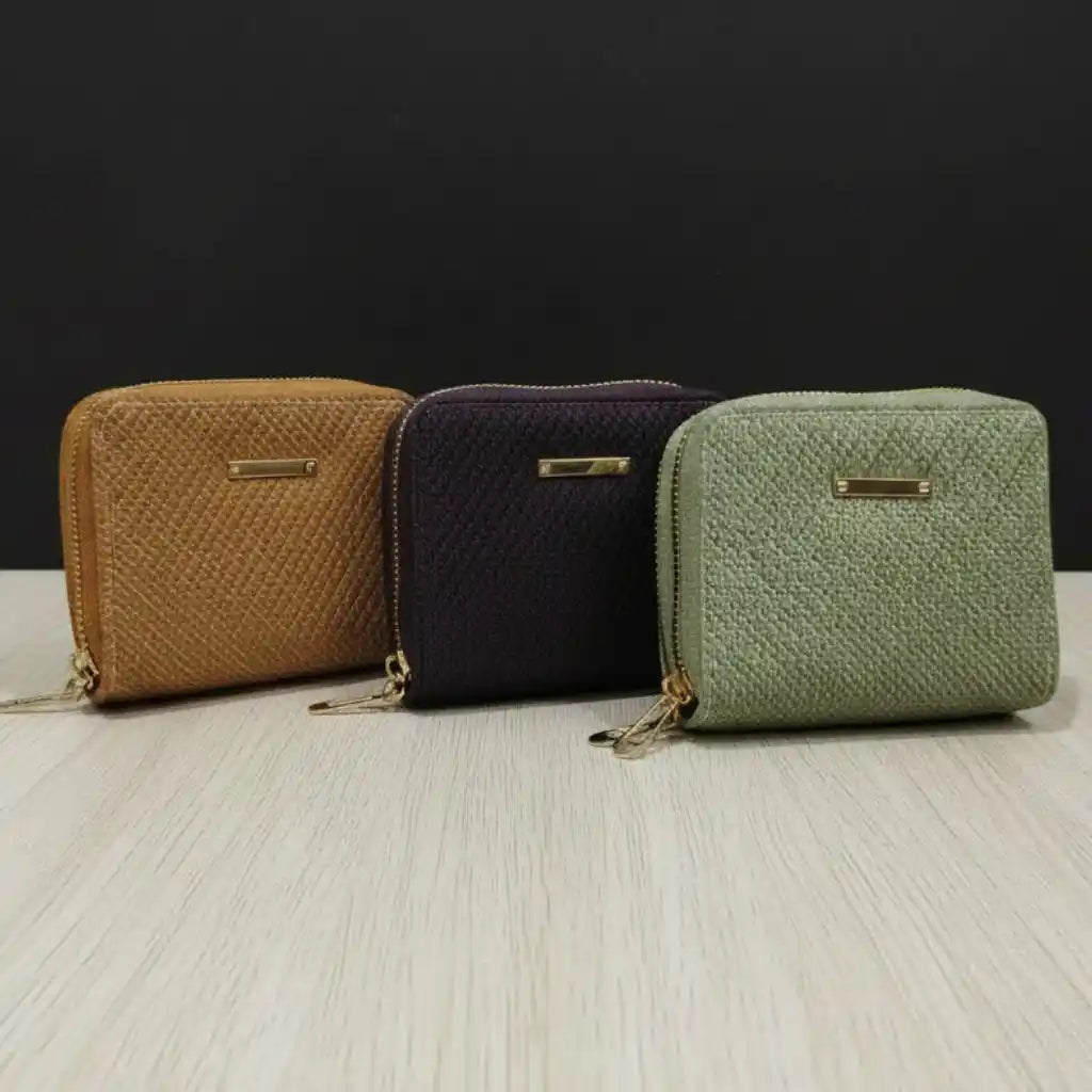 Three textured wallets in brown, black, and green on a light surface with a dark background.