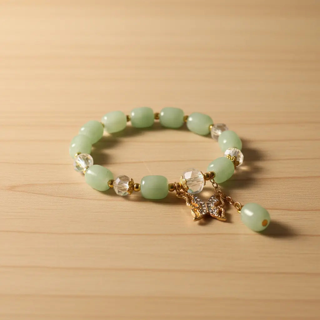 Green beaded bracelet with a gold charm on a wooden surface