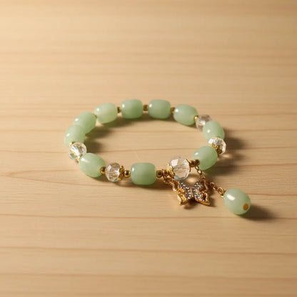 Green beaded bracelet with a gold charm on a wooden surface