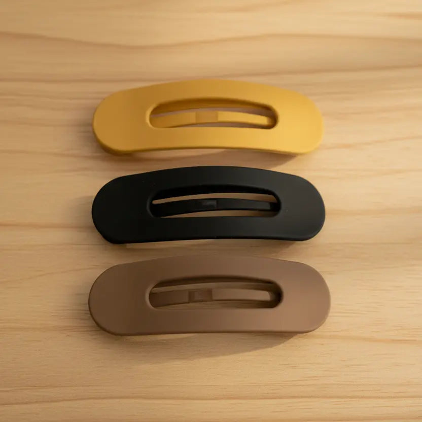 Three oval-shaped door handles in gold, black, and bronze on a wooden surface.