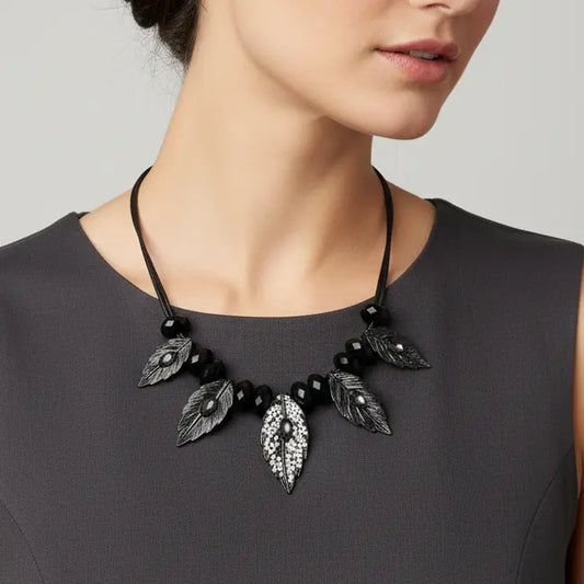 Black leaf-shaped necklace worn by a person on a plain background