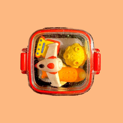 Colorful toy set in a transparent container with red lid on a peach background