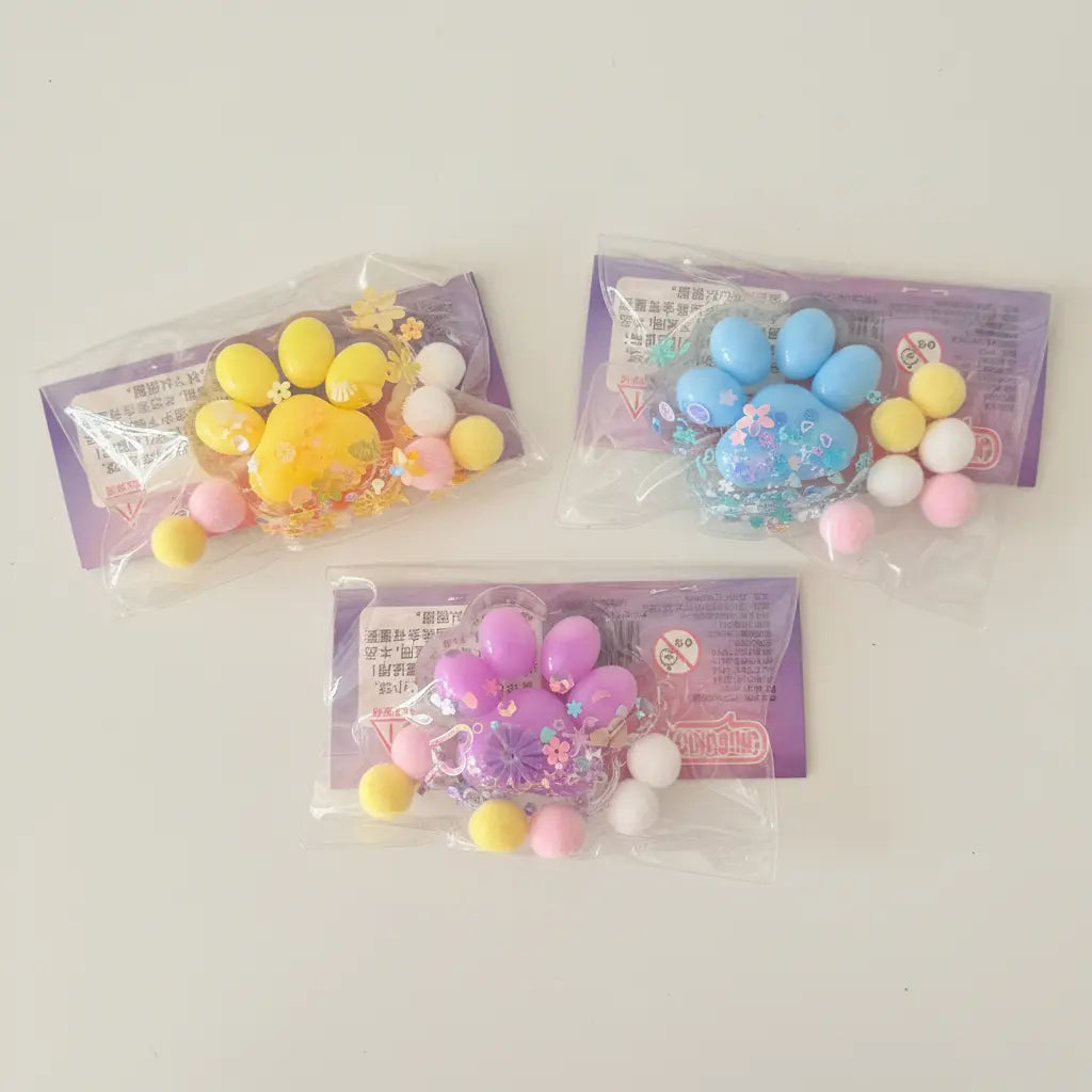 Three packages of colorful paw-shaped items on a wooden surface