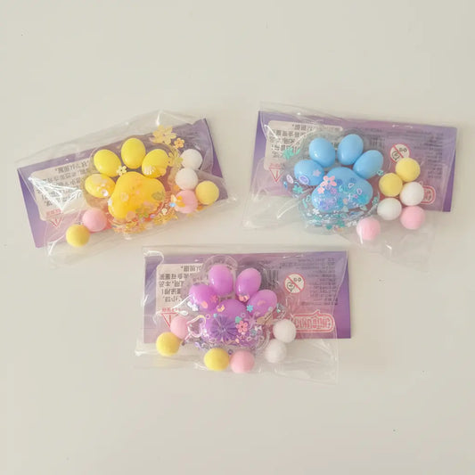 Three packages of colorful paw-shaped items on a wooden surface