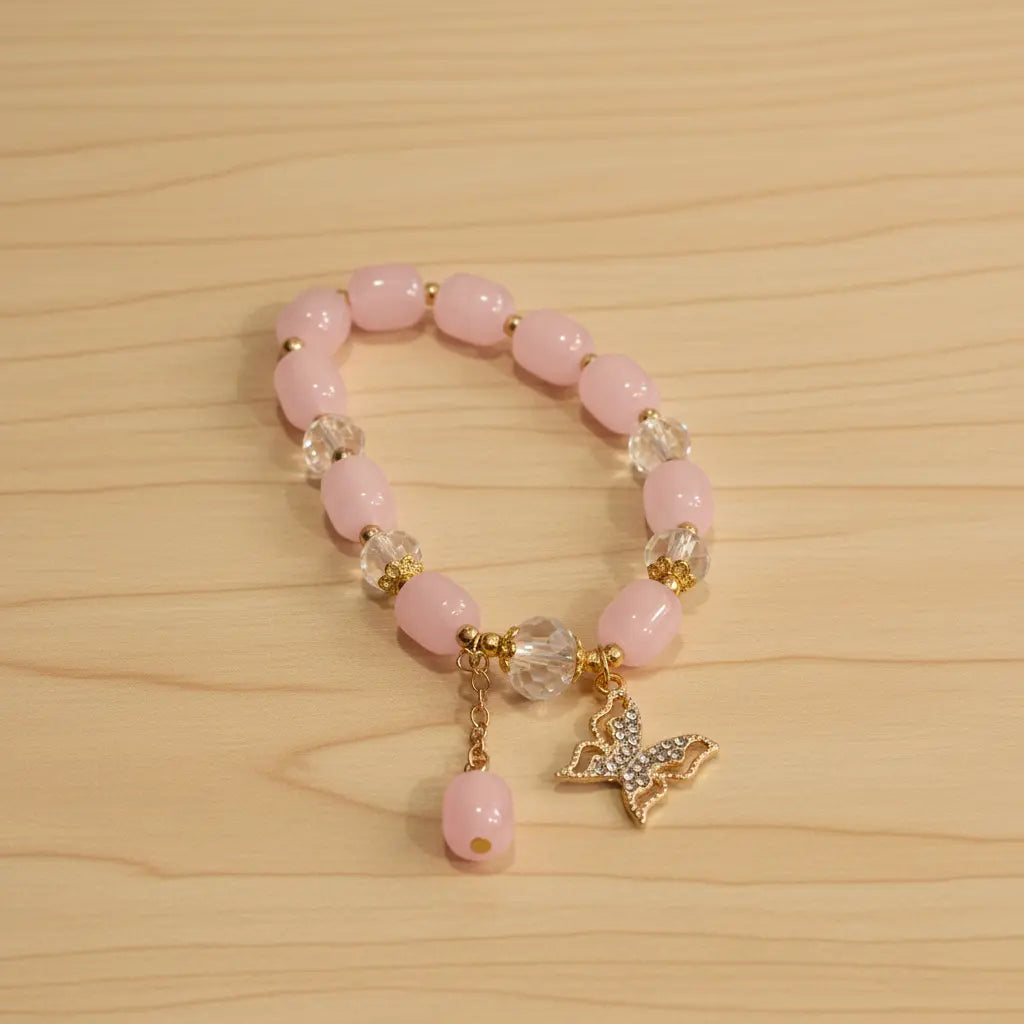 Pink beaded bracelet with butterfly charm on a wooden surface