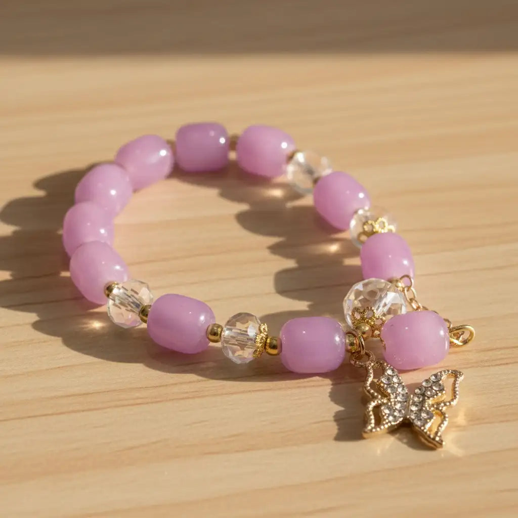 Pink beaded bracelet with a gold butterfly charm on a wooden surface