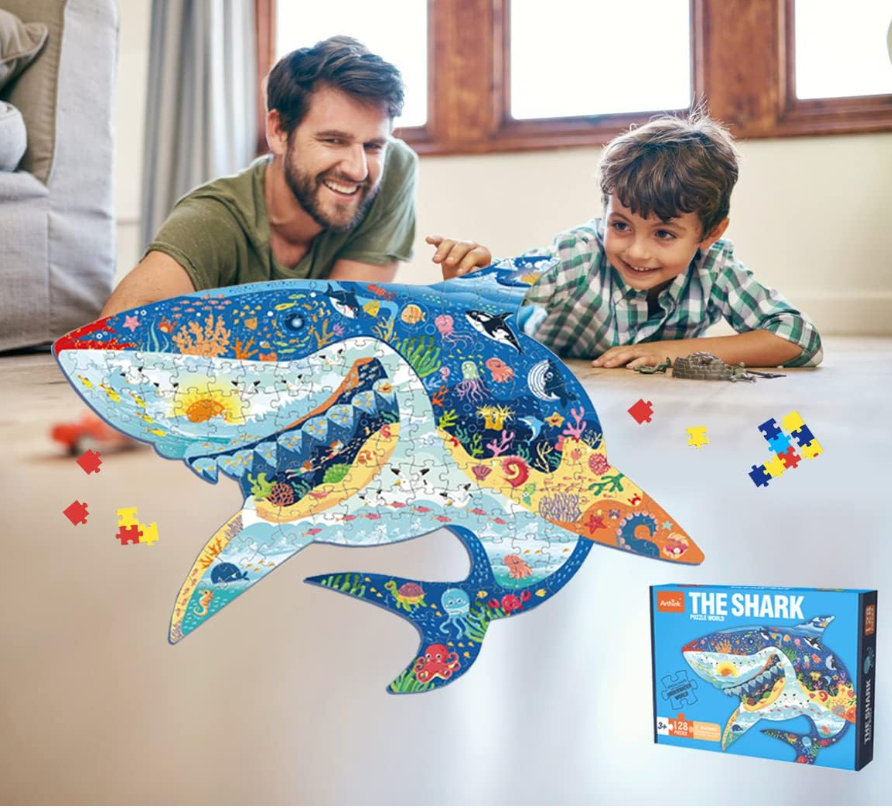 Man and child playing with a shark-shaped puzzle in a living room.
