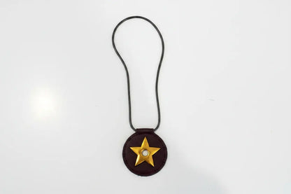 Brown leather charm with a gold star on a white background