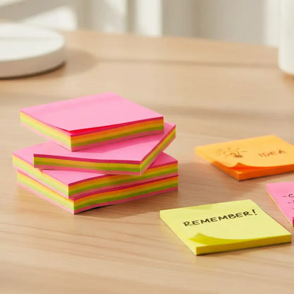 stack of neon sticky notes on a wood desk  with writing on it