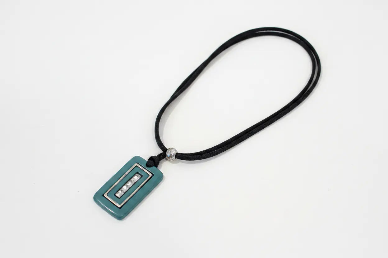 Teal pendant on a black cord against a white background