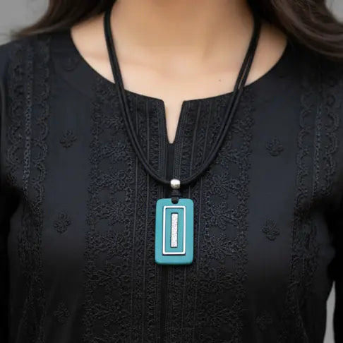 Person wearing a black top with a turquoise pendant necklace.