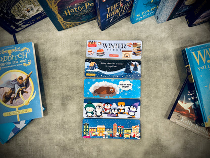vibrant set of 5 laminated card stock bookmarks with a winter theme on a surface surrounded by books with different shades of blue